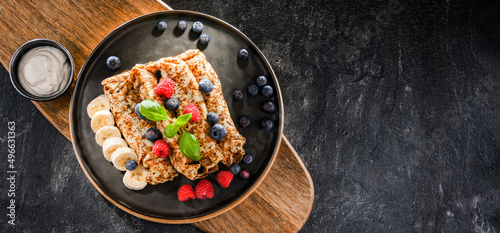 A plate of pancakes with cheese and fruits