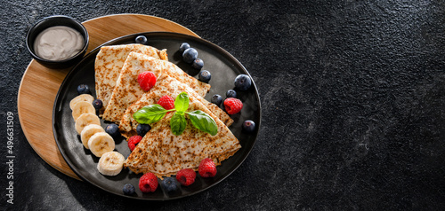 A plate of pancakes with cheese and fruits