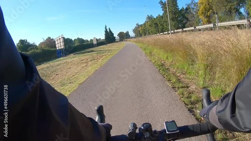 Bike ride along asphalt bike path outside in nature past highway on sunny day, first person view