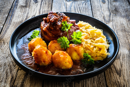 Fotografie Roast pork knuckle with potatoes and fried cabbage   on wooden table