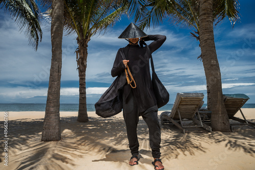Man wearing in black codtume next to palms At Beach