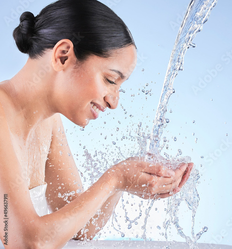 We all want that natural healthy glow. Shot of a young woman washing herself against a blue background.
