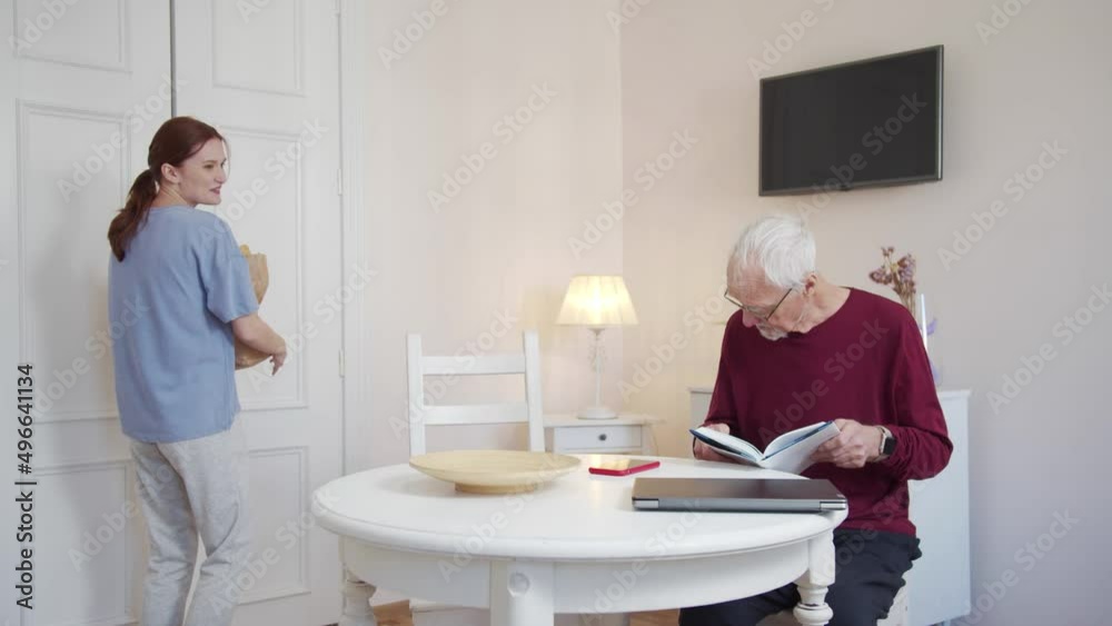 The granddaughter comes to visit her grandfather with gifts. The man happily hugs her The granddaughter comes to visit her grandfather with gifts. The man happily hugs her