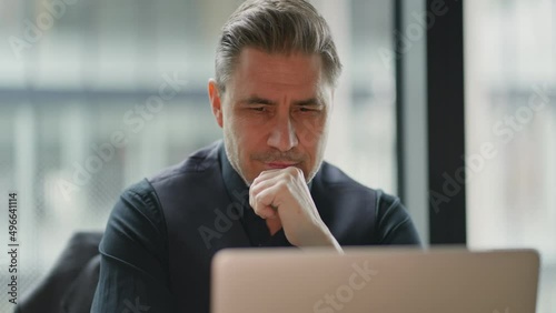 Businessman using laptop computer in office. Happy middle aged man, entrepreneur, small business owner working online, thinking.