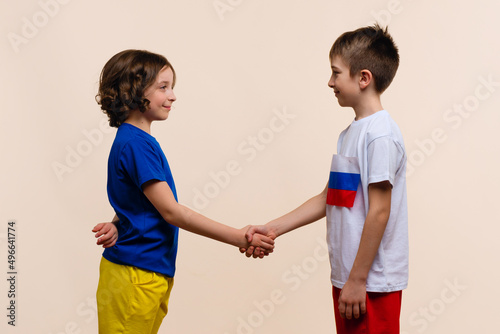 Boy and Girl in Outfits in Colors Flags Russia and Ukraine Look each Other and Make Handshake. Reconciliation, end conflict and stop war. Friendship of Fraternal Peoples. Cousins want peace