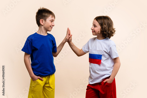 Boy and Girl in Outfits in Colors Flags Russia and Ukraine Look Each Other, Giving High Five and Agree on Truce. Concept Successful Negotiations to Peace-making. Friendship of Fraternal Peoples photo