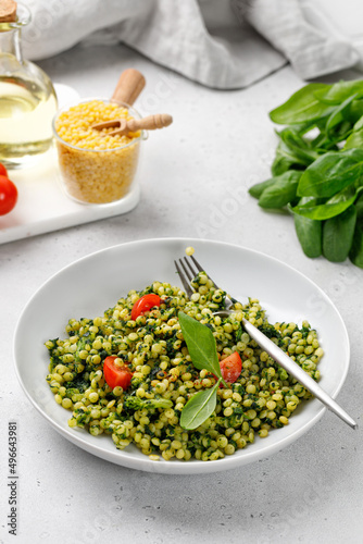 Israel couscous, green ptitim dish with spinach and broccoli, cherry tomatoes. Vegan, Traditional Israeli pasta.