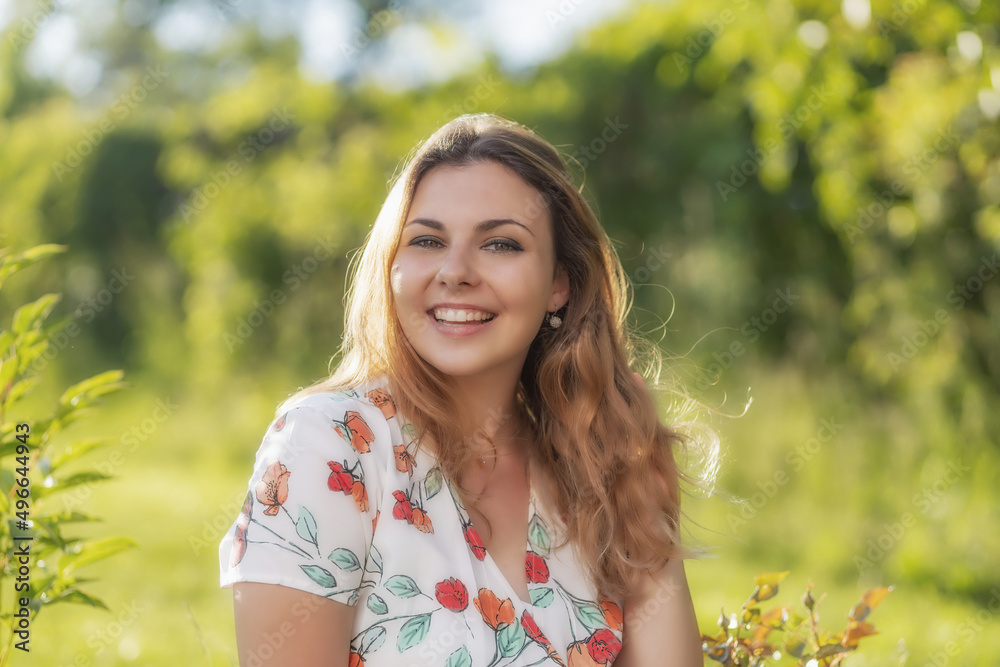 Smiling beautiful young woman is posing outdoors in summer day. Horizontally. Smiling beautiful young woman is posing outdoors in summer day. Horizontally.