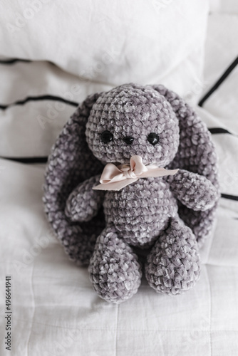 Knitted bunny of gray color in the interior of a bright apartment