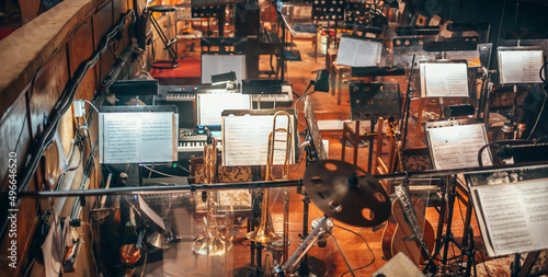 Orchestra pit. Musical instruments. Notebooks with sheet music, music stand. Warm soft light. Guitar, drums, trumpet, keyboards. photo