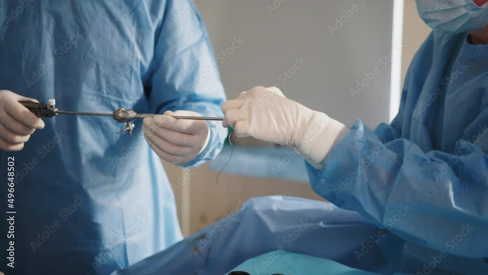 A team of surgeons stitches the patient's skin using a needle holder