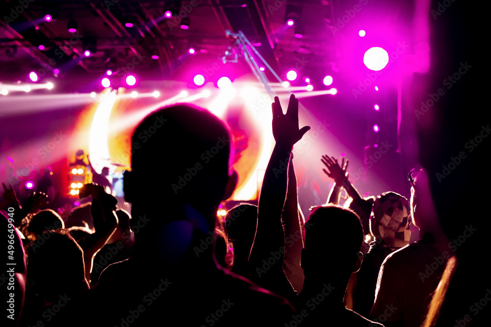 A girl with raised hands enjoys a rock concert.