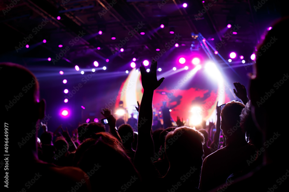 Rock concert, silhouettes of happy people raising up hands.