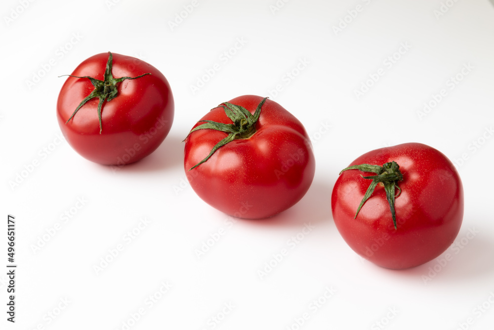 Row of three red tomatoes isolated on a white background