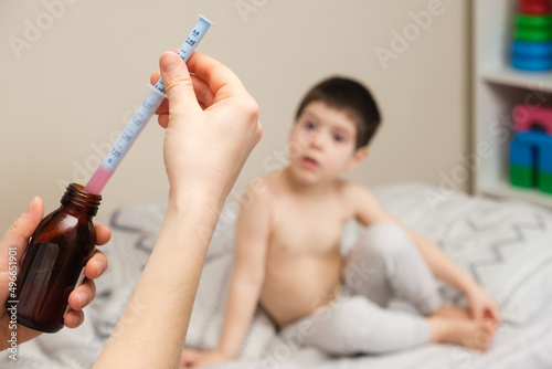 The pediatrician or mother types in a measuring syringe the medicine for cough or temperature syrup for the child photo