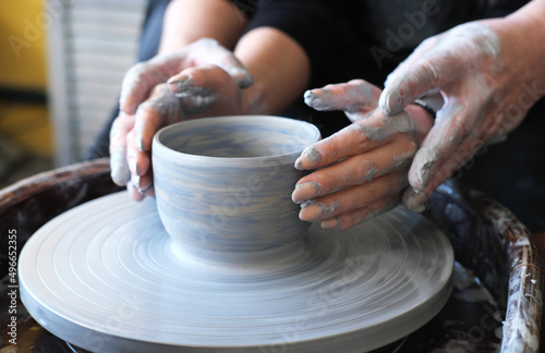 Male and female hands make a vase of clay. Date in the workshop