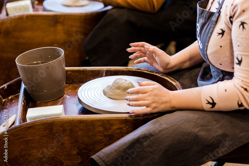 The hands of a female potter making clay dishes by a pottery wheel