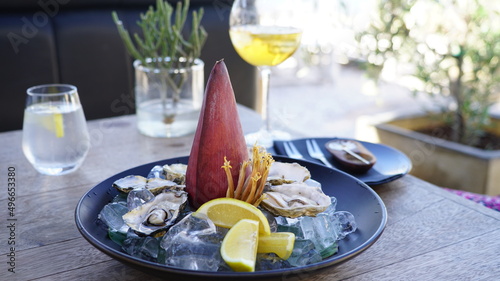 ein Teller Austern mit schöner Dekoration und einem Glas Wein