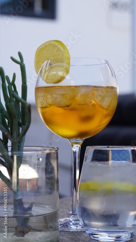 ein Glas Cider mit Zitrone und Eis auf einem Tisch mit Wassergläsern und Pflanze