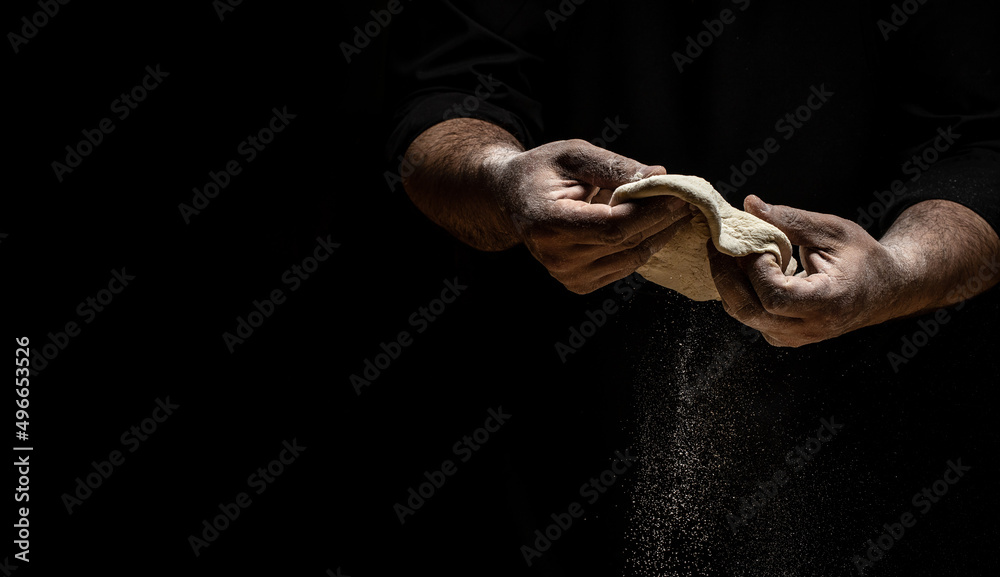 Beautiful and strong men's hands knead the dough make bread, pasta or pizza. Powdery flour flying into air. chef hands with flour in a freeze motion of a cloud of flour midair