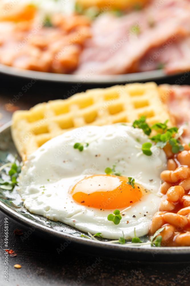 Potato waffles with fried egg, bacon and baked beans. Morning breakfast Potato waffles with fried egg, bacon and baked beans. Morning breakfast