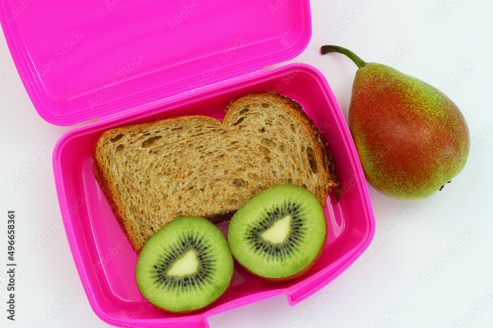 Lunchbox containing brown bread sandwich, two kiwi halves and pear on white background