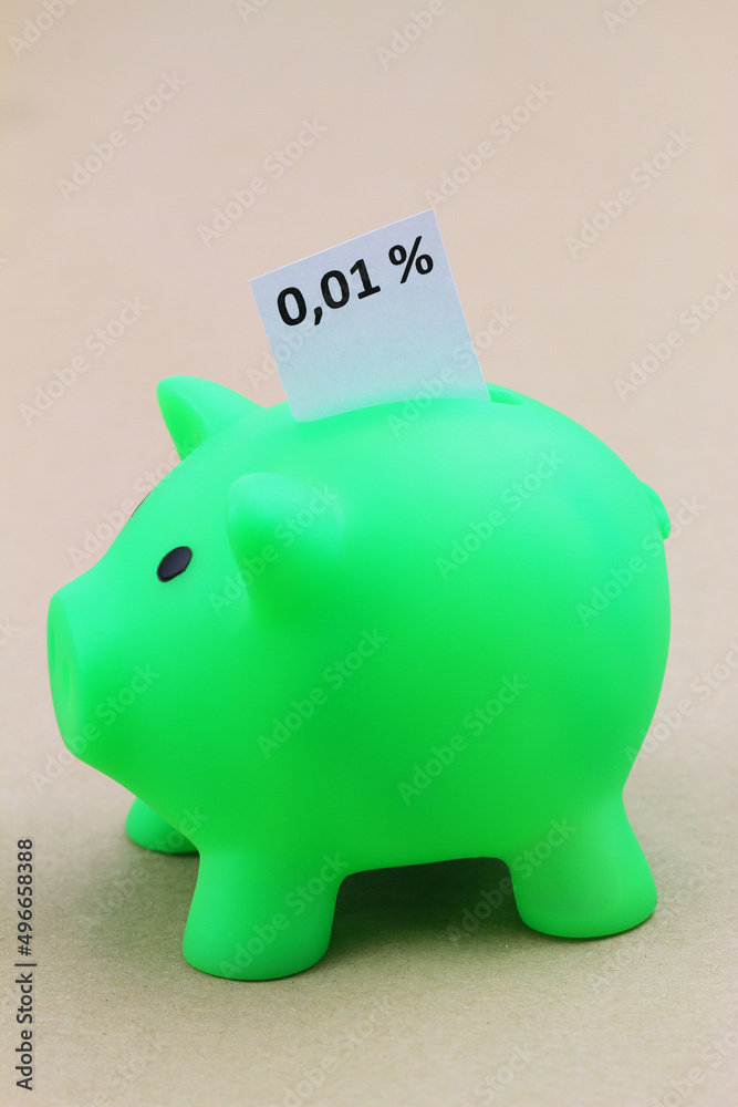 Piggy bank with interest rate 0,01% written on white paper