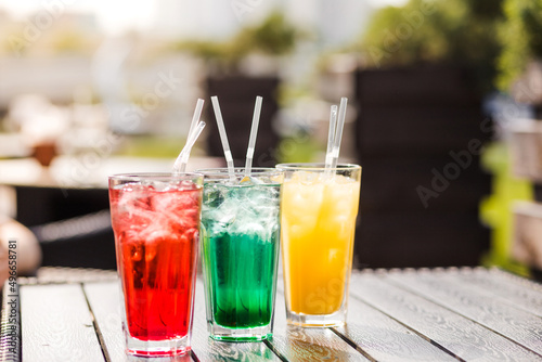 colorful cocktails with straw are on the street on the table in a cafe in summertime daylight