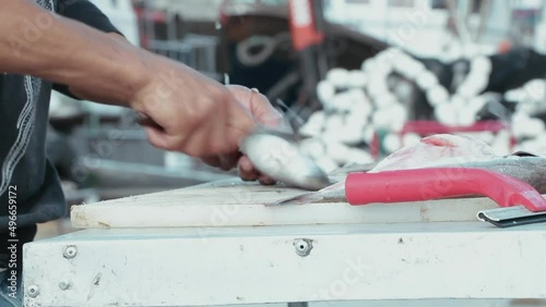 View of a young man cleaning fish on a table in the port.