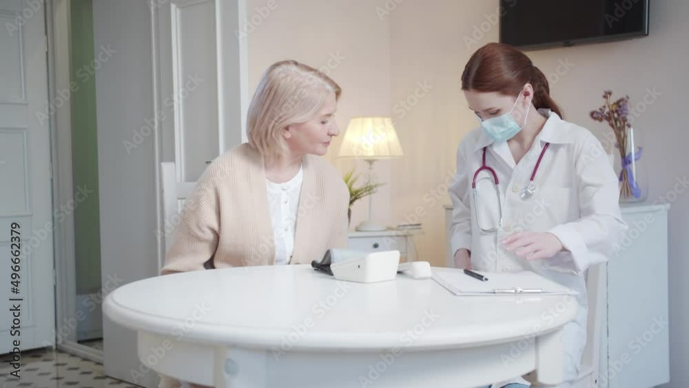 A female doctor in a white coat comes to an appointment with an elderly woman A female doctor in a white coat comes to an appointment with an elderly woman