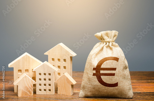 Houses and euro money bag. Investments in real estate and construction industry. Energy efficiency and costs for heating and home services. Community municipal budget. photo