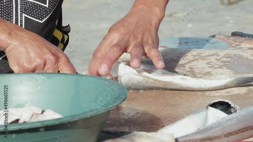 View of a young man cleaning fish on a table in the port.