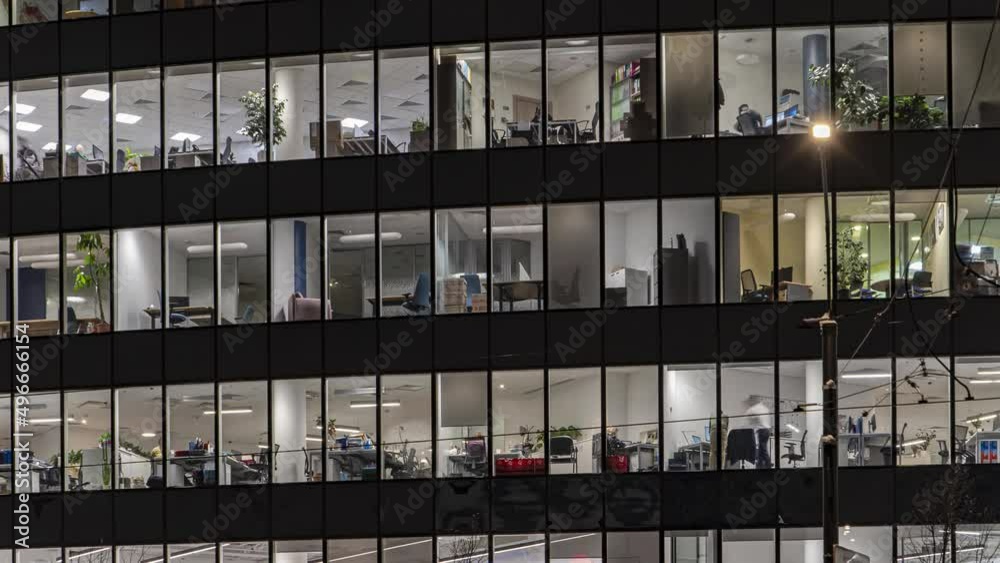 Office workers, during operation and at the end of the working day, visible through the windows of the business center, time lapse Office workers, during operation and at the end of the working day, visible through the windows of the business center, time lapse