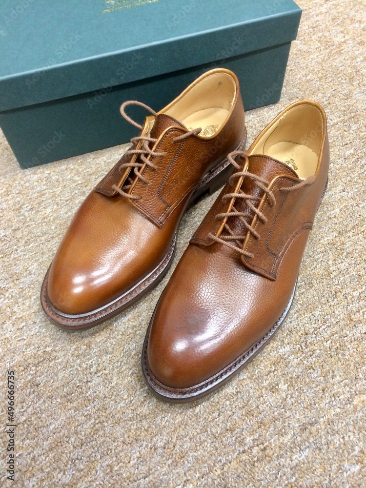 New brown leather shoes in front of the green box