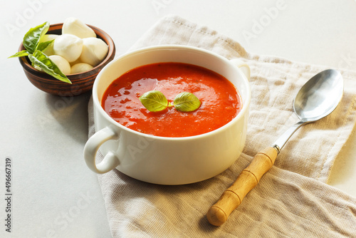 Fotografie Italian tomato soup with mozzarella and basil on a textile napkin