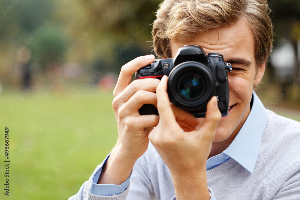 Finding the perfect subject matter. Shot of a young man taking photos in a park. Finding the perfect subject matter. Shot of a young man taking photos in a park.