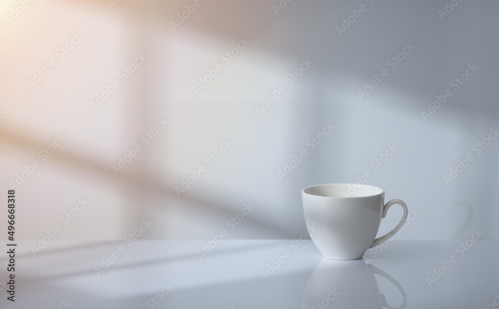 Coffee cup on table with window light and shadow drop on white wall background