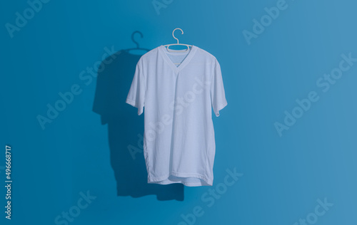 White tshirt with hanger. Flying cotton T-shirt against a blue background