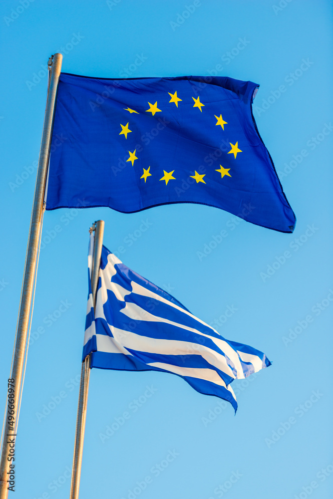 Greece and EU relations. Greek and European Union flags waving on clear blue sky Greece and EU relations. Greek and European Union flags waving on clear blue sky