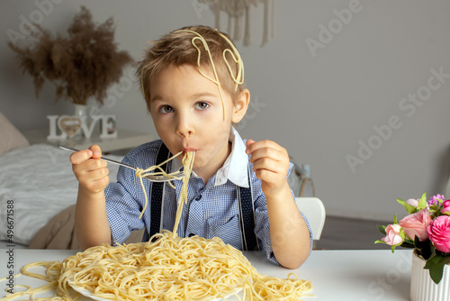 Cute preschool child  blond boy  eating spaghetti at home  making a mess everywhere