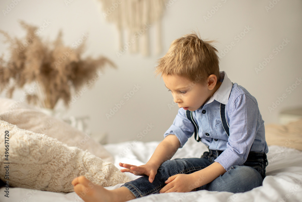 Fototapeta premium Beautiful fashion preschool child, boy, having fun at home in bed, looking out of the window