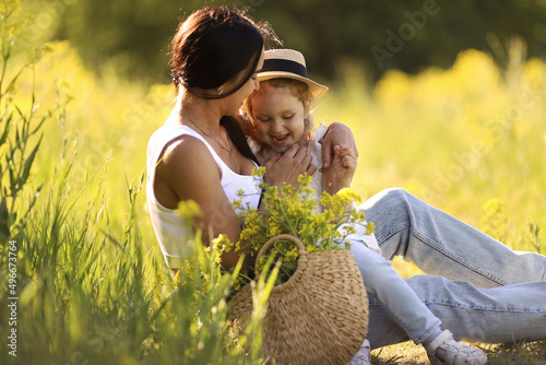 Mother and little daughter having fun in summer meadow with yellow flowers. Happy family on summer. Concept of healthy family without allergies. High quality photo. 