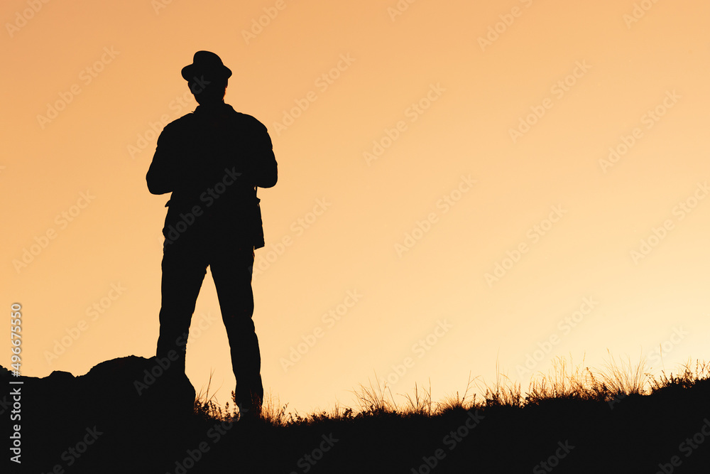 silhouette of man in hat standing on orange background