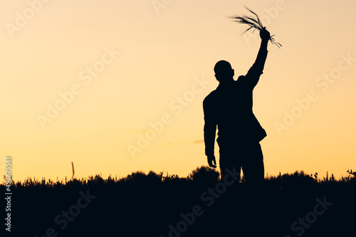 silhouette of a man raising spikelets of rye in his hand against the backdrop of sunset. the harvest is ripe it s time to harvest