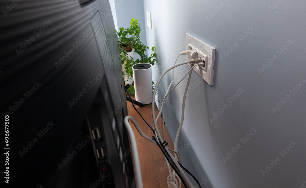 Home related do it yourself activities. Cable management for the power outlet, internet and TV wires hidden behind the smart tv on a wooden console in a flat.