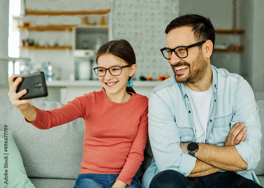Obraz premium child daughter girl family happy father selfie camera phone smartphone mobile having fun together girl smiling home bonding love