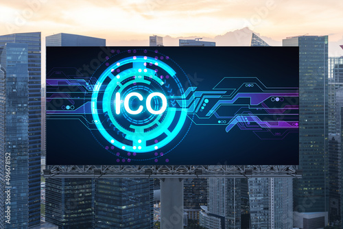 ICO hologram icon on billboard over panorama city view of Singapore at sunset. The hub of blockchain projects in Southeast Asia. The concept of initial coin offering, decentralized finance