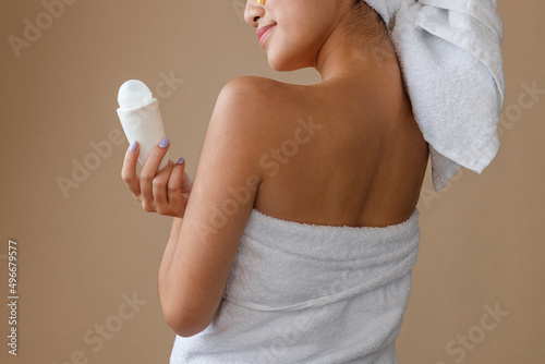 Young woman with deodorant standing in studio photo