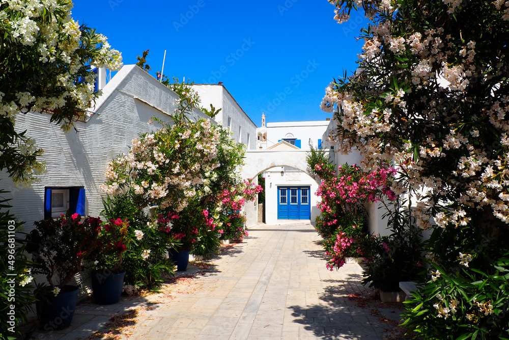 Fototapeta premium One of the charms of the Cyclades (here, in Pyrgos on the island of Tinos), in the heart of the Aegean Sea, are the narrow streets: white houses, colorful doors, flowery balconies and cobbled streets