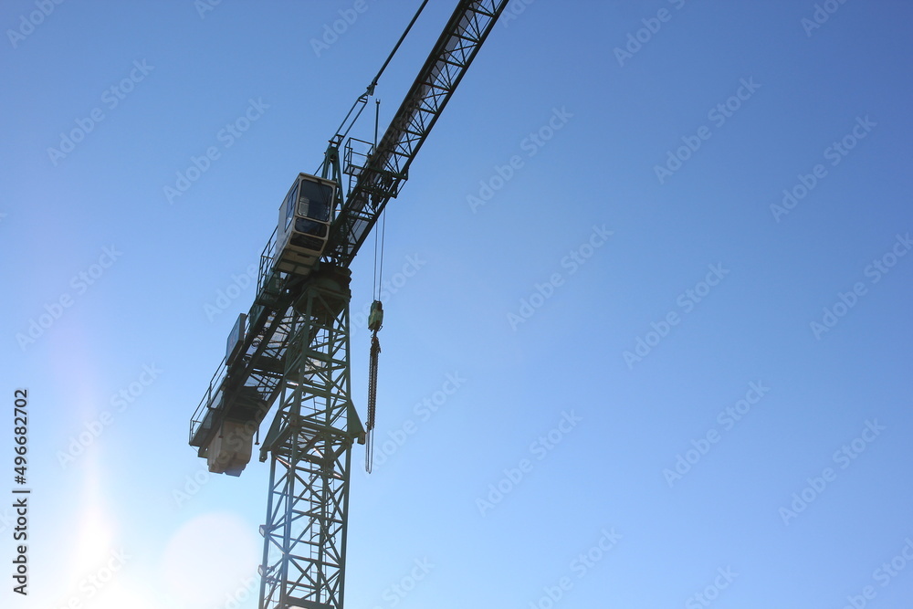 Silhouette of the construction crane against a blue sky